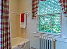Custom window treatments and shower curtain complement the tub and shower combination